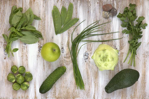 Set of green vegetables on white painted wooden background: kohlrabi, avocado, brussels sprouts, apple, cucumber, green onion, pea pods, parsley, basil. — Stock Photo, Image