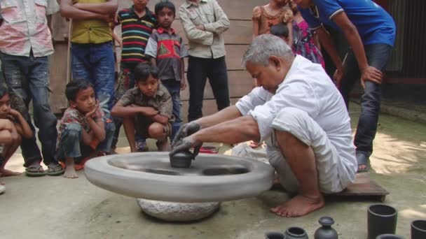 Bangladeshi Mann demonstriert Kindern Prozess der Tonkeramikproduktion in einem traditionellen Stil in Tangail, bangladesh. — Stockvideo