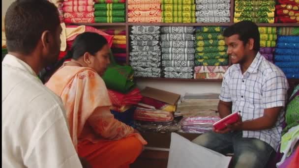 As pessoas negociam o preço de um pano de impressão de selo no workshop no Novo Mercado em Daca, Bangladesh . — Vídeo de Stock