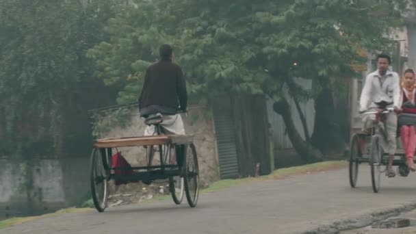 Ludzie jeździć rowery przez ulicę na zimno mglisty poranek w Puthia, Bangladesz. — Wideo stockowe