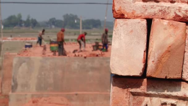 Montón de ladrillos con gente trabajando en la fábrica de ladrillos en el fondo en Dhaka, Bangladesh . — Vídeo de stock