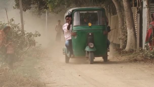 Les gens montent un trois-roues par une route de campagne poussiéreuse à Tangail, Bangladesh . — Video