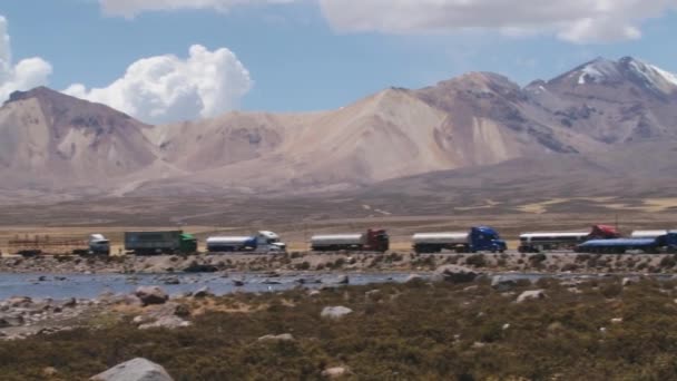 Vrachtwagens wachten in de rij voor de grensovergang Bolivia-Chili in Putre Chili. — Stockvideo