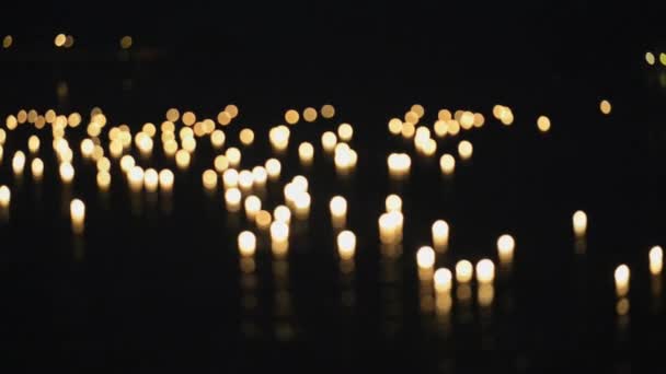 Velas ardientes flotan en el agua durante la celebración de Loi Khrathong en Sukhothai, Tailandia. Dentro y fuera de foco . — Vídeo de stock