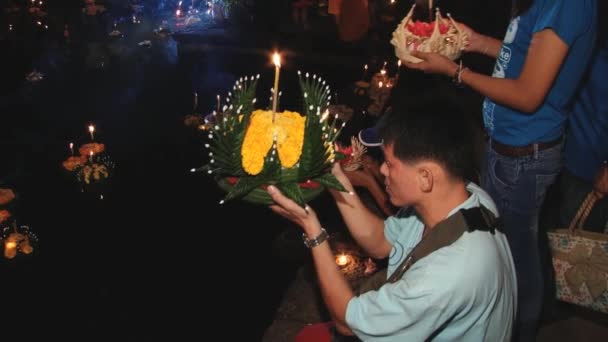 Menschen beten und stellen schwimmende Kerzen auf Wasser während der Loi Krathong Feierlichkeiten in Sukhothai, Thailand. — Stockvideo
