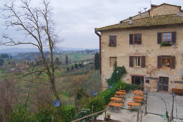 Exterior of the medieval building with a restaurant in early spring in San Gimignano, Italy. — Stock Photo, Image