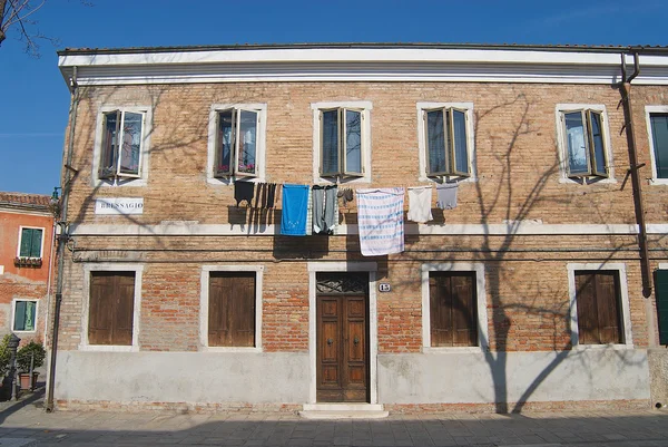 Außenseite der Fassade eines Wohnhauses mit gewaschenen Kleidern, die draußen in Murano hängen, Italien. — Stockfoto