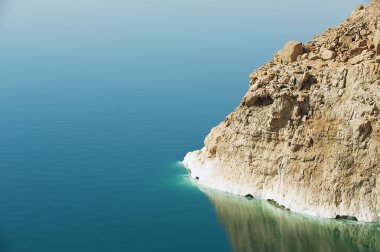 View to the cliff at the Dead sea shore with reflection in the water in Jordan.