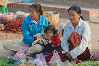 Women with the kid sell vegetables at the food market in Luang Prabang, Laos. clipart