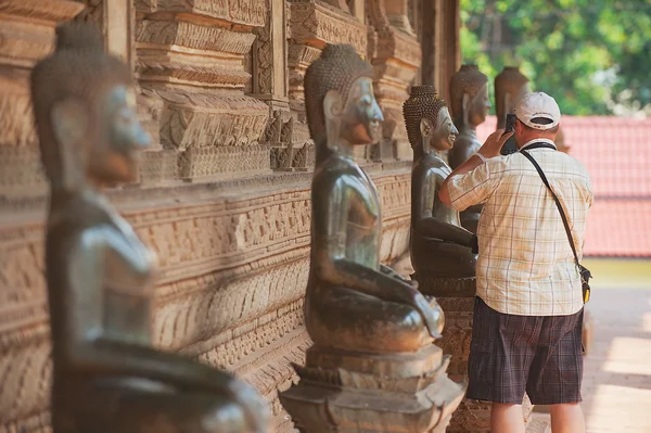 Tourist makes photo of the Buddha statue outside of Hor Phra Keo temple in Vientiane, Laos. — Stockfoto