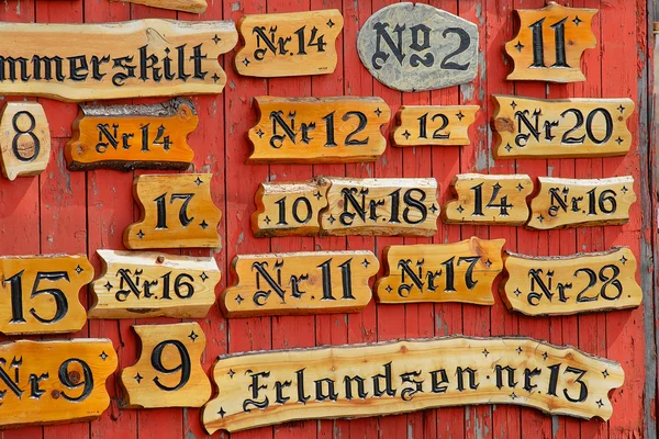 Collection of the wooden house numbers against the red painted wall. — Stok fotoğraf