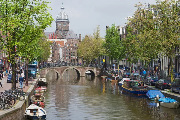 Pohled do kanálu s bazilikou svatého Mikuláše na pozadí v Amsterdamu, Nizozemsko. — Stock fotografie
