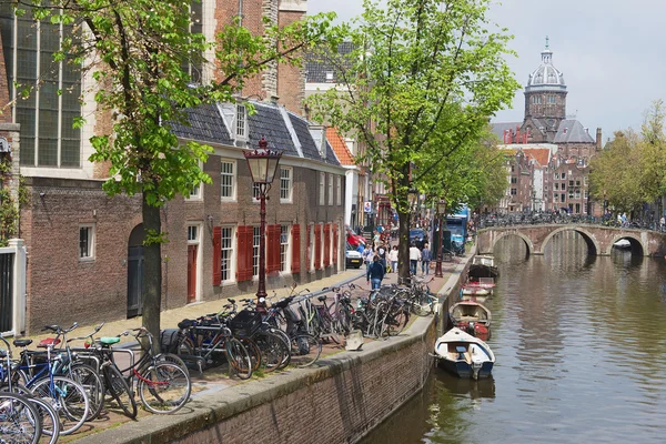 Veduta del canale con biciclette parcheggiate e basilica di San Nicola sullo sfondo ad Amsterdam, Paesi Bassi . — Foto Stock