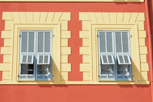 Bella casa in stucco rosso con due tradizionali finestre francesi blu a Nizza, Francia . — Foto Stock