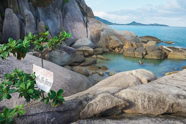 "Dikkat, kaygan" Koh Samui, Tayland at işareti ile deniz kenarında taşlar için görüntüleyin. — Stok fotoğraf