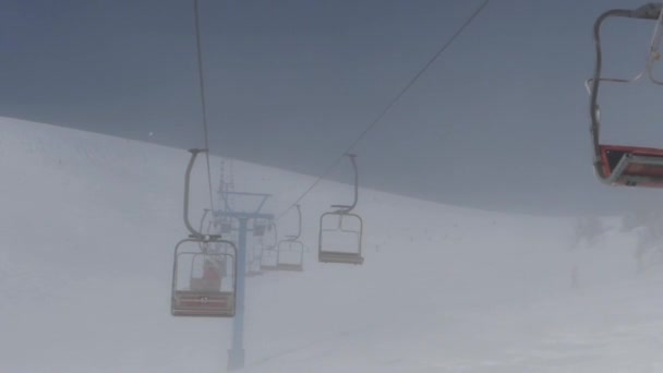 I sedili e la barra blu della seggiovia nella nebbia. Comprensorio sciistico in montagna . — Video Stock