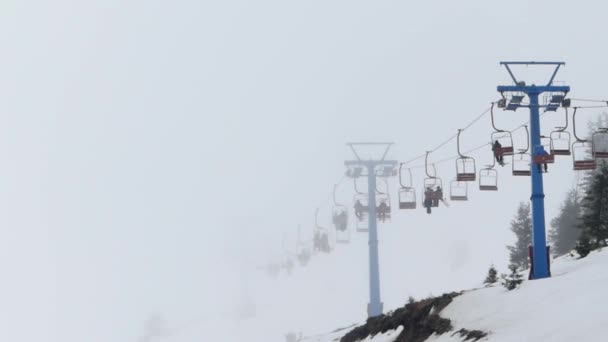 Seggiovia nella nebbia che trasporta le persone in cima alla montagna . — Video Stock