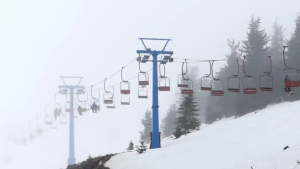 Chaise élévatrice dans le brouillard transportant les gens au sommet de la montagne . — Video