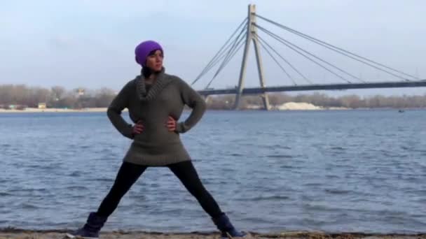 Chica de pie en pose de yoga. Al fondo el puente y el río . — Vídeos de Stock