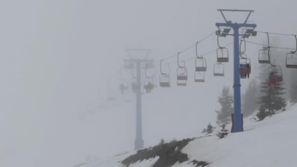 Ski lift lyfter människor till toppen av berget i dimma väder. — Stockvideo