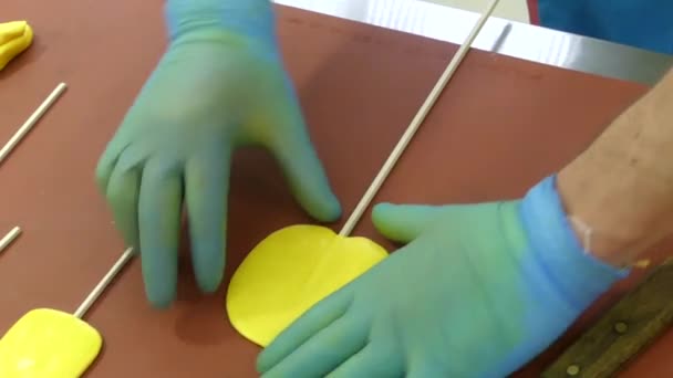 As mãos em luvas especiais fazem forma redonda de caramelo amarelo na mesa . — Vídeo de Stock