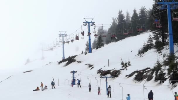 Brouillard dans une station de ski. Ascenseurs de chaise et de surface transportant des personnes . — Video