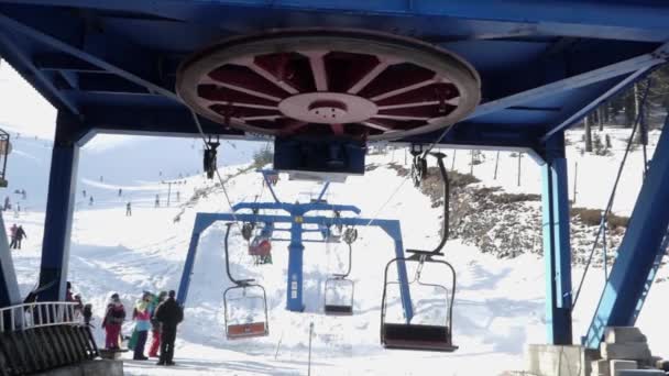 Wiel van stoellift station op ski-oord. Mensen zitten in de stoelen. — Stockvideo