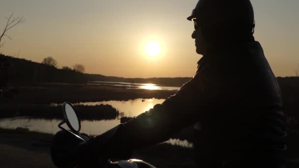 Motociclista sentado en la motocicleta al atardecer . — Vídeo de stock