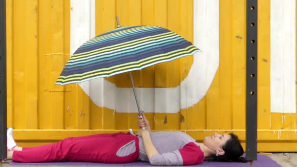 Het meisje ligt op de rug en opent de paraplu. — Stockvideo