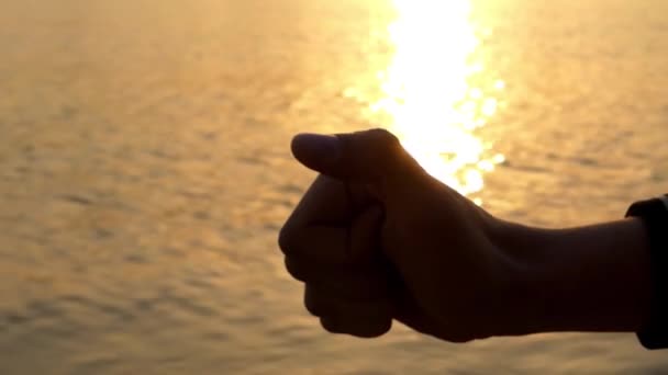 Hand maken zoals bij zonsondergang. Zee op de achtergrond. — Stockvideo