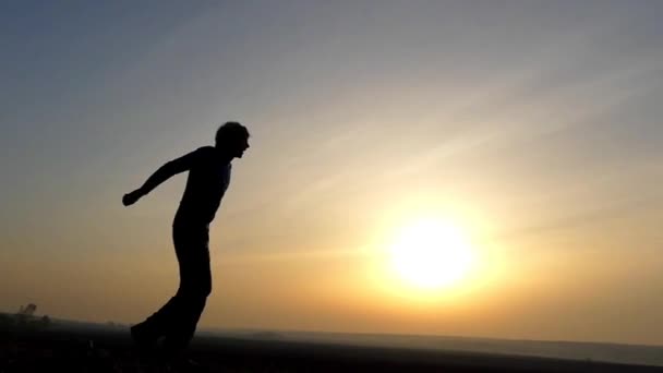 Um homem salta para o céu ao pôr-do-sol. Movimento lento . — Vídeo de Stock