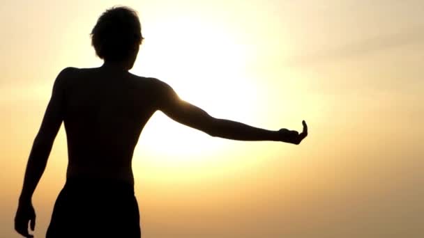 Magere jongen tonen Biceps bij zonsondergang. — Stockvideo