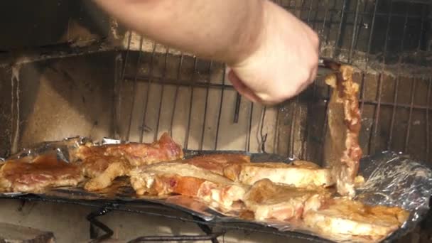 Hand med tång för sätta kött på grillen. — Stockvideo