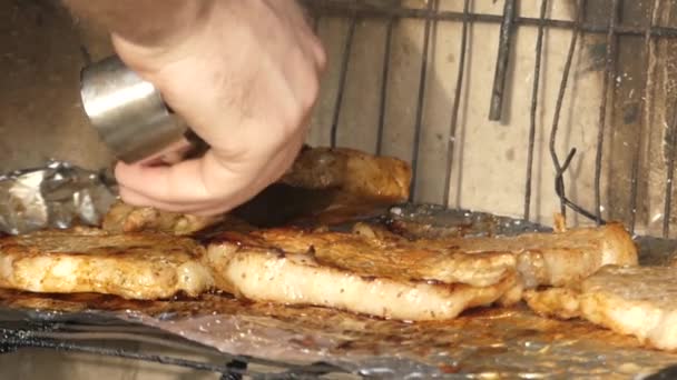 Hand med tång för sätta kött på grillen. — Stockvideo