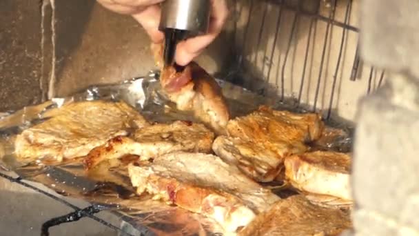 Mano utilizzando pinze per accendere la carne alla griglia . — Video Stock