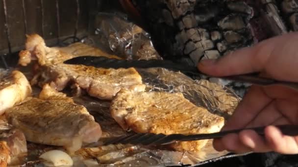 Χέρι χρησιμοποιώντας λαβίδα για να μετατραπεί το κρέας στη σχάρα. — Αρχείο Βίντεο