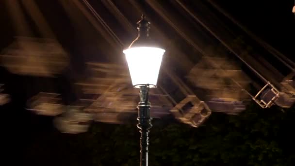 Noční lampu a rozmazané kolotoč v zábavním parku. — Stock video