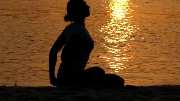 Meisje praktijk Lotos Pose op het strand bij zonsondergang. — Stockvideo