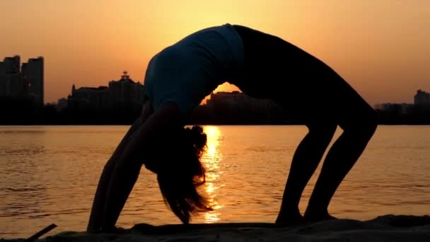 Mädchen üben Rad Pose am Strand bei Sonnenuntergang. — Stockvideo