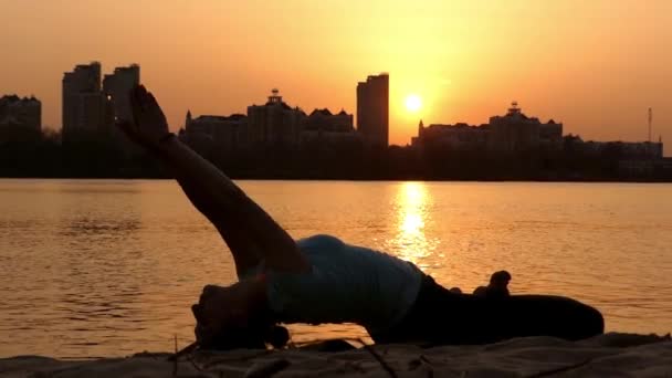 Mädchen üben lotos posieren am Strand bei Sonnenuntergang. — Stockvideo