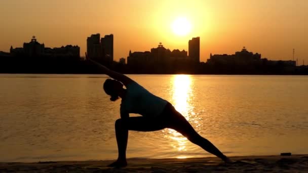 Yoga yaparken kız üçgeni oluşturmaktadır. Günbatımı. — Stok video