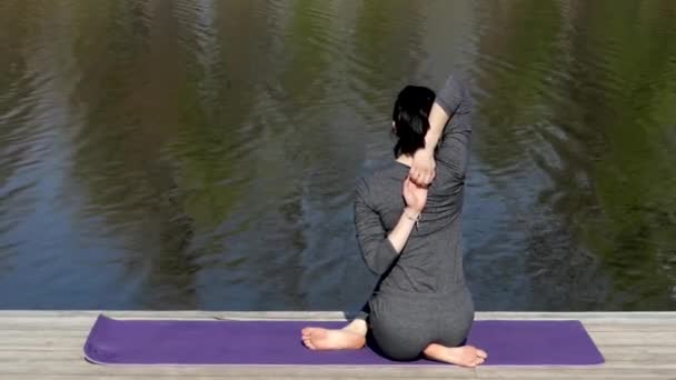 Profesora de Yoga hace una postura de vaca cerca del agua . — Vídeo de stock