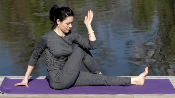 Mädchen machen matsyendrasana in der Nähe von Wasser. — Stockvideo