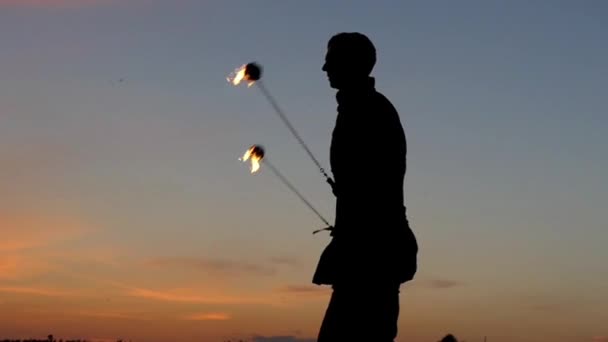 Brand Show bij zonsondergang. Man gebruikt Poi aan het maken van mooie effecten. Slow Motion. — Stockvideo