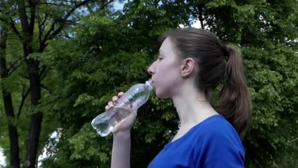 Jeune fille en robe bleue boit de l'eau de la bouteille . — Video