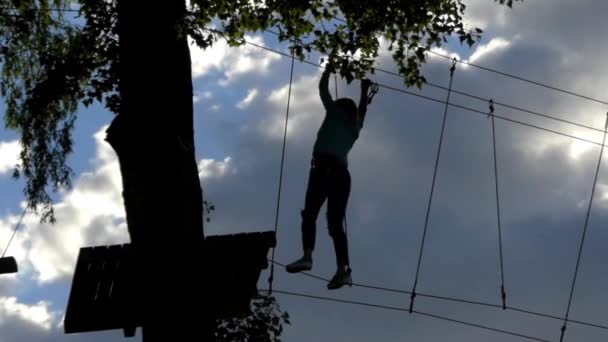 Girl on High Altitude Goes Through the Ropes. Entretenimiento en el parque de cuerdas . — Vídeos de Stock