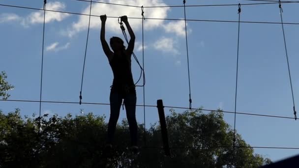 Meisje op grote hoogte doorloopt in de touwen. Entertainment in het touwbaanparcours. — Stockvideo