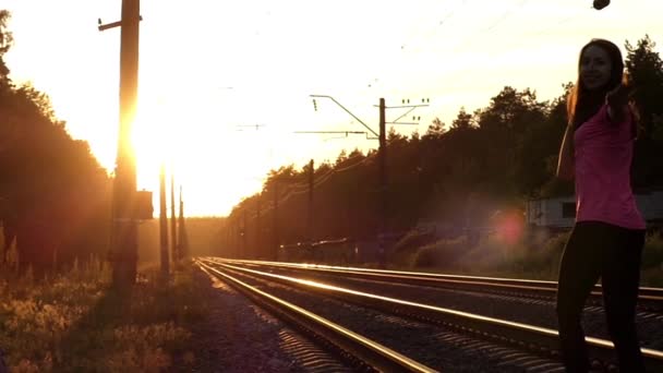 Slender Girl caminha em uma estrada de ferro ao pôr do sol . — Vídeo de Stock