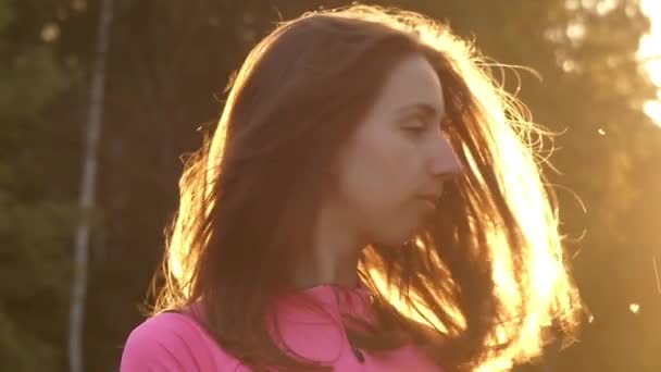 Una giovane ragazza in slow motion scuotere la testa e giocare con i capelli. l'azione si svolge al tramonto . — Video Stock