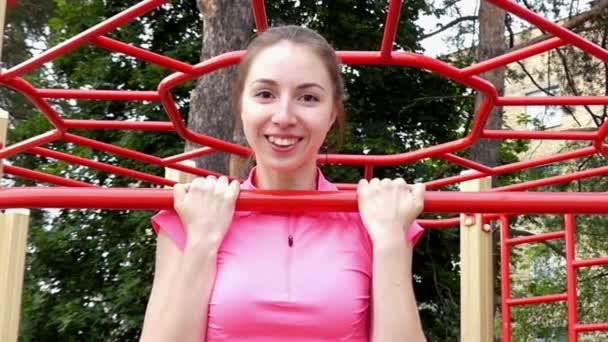 Menina jovem e bonita pendurado no bar e sorrisos. Depois, ela salta para baixo. Movimento lento . — Vídeo de Stock